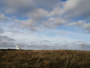 Lonely white lighthouse against big sky with clouds