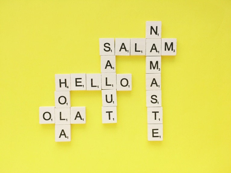 Scrabble tile formation with word hello in different languages against yellow background