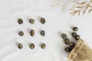 Rune stones for fortune telling set out on a white background and spilling out of a hessian bag