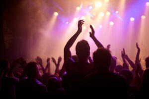 Rear view of a music fan dancing with her arms raised at a music concert