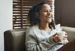 Woman enjoying music on her sofa holding white mug