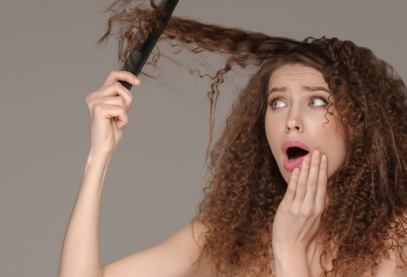 girl trying to brush her long curly hair