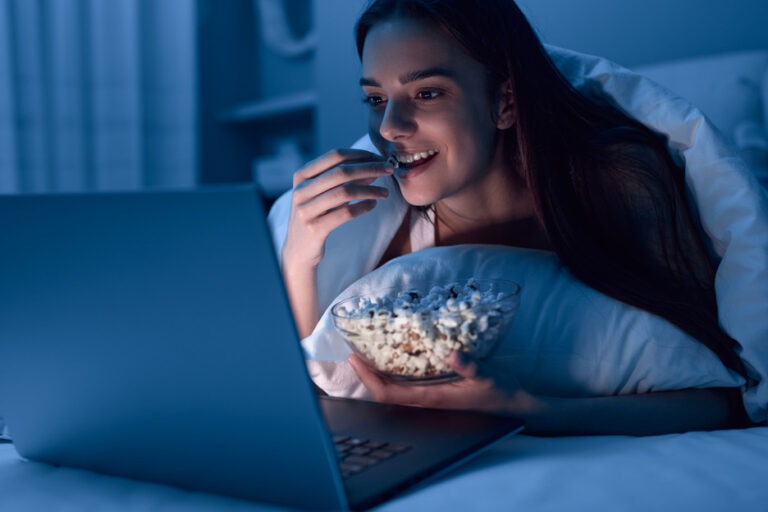 girl watching feelgood film in bed eating popcorn