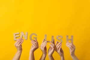 hands holding up wooden letters to spell the word English