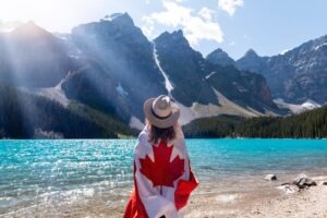 Woman with Canadian flag at a mountain lake in the Rockies